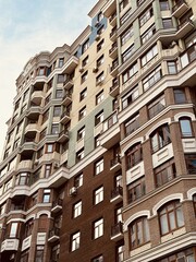 Fototapeta premium Elegant Urban Building Exterior, Modern City Residence With Decorative Features, Sophisticated City Apartment Complex Showcasing Ornate Brickwork And Scenic Cityscape Backdrop