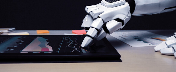 A close-up of a robotic hand engaging with a touchscreen interface, displaying colorful graphs and data, symbolizing advanced technology and modern workspace innovation.Noogenesis