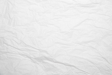 Obraz premium Primer plano de hoja de papel blanco con arrugas, pliegues y dobleces sobre superficie texturizada.imperfección y reutilización, simbolizando fragilidad, memoria y naturaleza táctil del material.