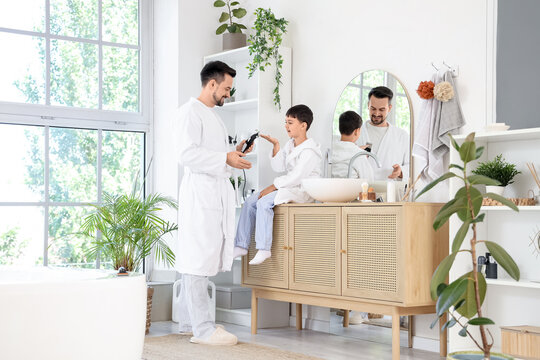 Happy father and his little son with trimmer shaving in bathroom