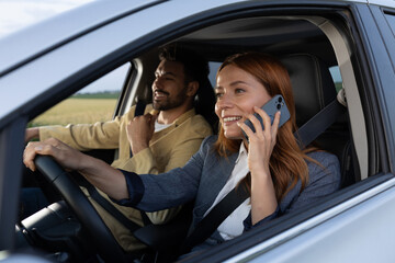 Businesswoman taking a phone call while driving with friend