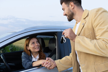 Handshake between woman and car salesman giving her the keys