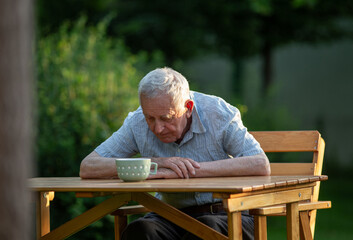 Senior sitting outside hunched over table