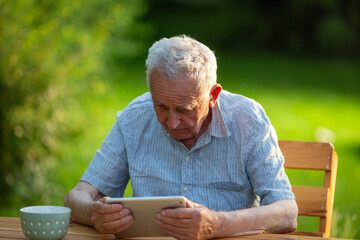 Senior man looking at his tablet outdoors
