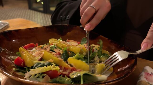 Person enjoying savory lula kebab with crispy french fries and fresh salad, using fork while dining in casual restaurant setting