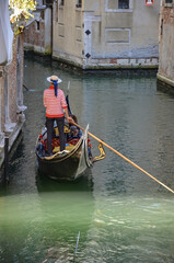 Italy, Venice, September 29, 2025,  A gondolier in a red and white striped shirt is transporting tourists in Venice