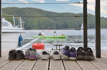 Tourists&rsquo; shoes left on a wooden pier at a yacht marina. Calm summer atmosphere by the water, symbol of vacation, relaxation, freedom, and leisure travel. No people.