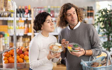 Naklejka premium Husband and wife choose poke together for a homemade lunch at the supermarket