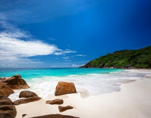 a pristine white sand beach with turquoise waters and dramatic dark colored rocks stretches towards a vivid blue sky creating a breathtaking tropical paradise
