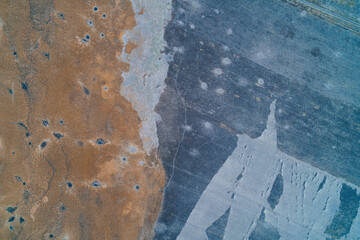 Frozen wetland patterns with white ice and brown reeds creating natural geometry aerial top down view