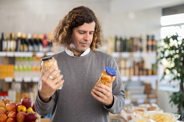 Male buyer choosing cans of beans in supermarket