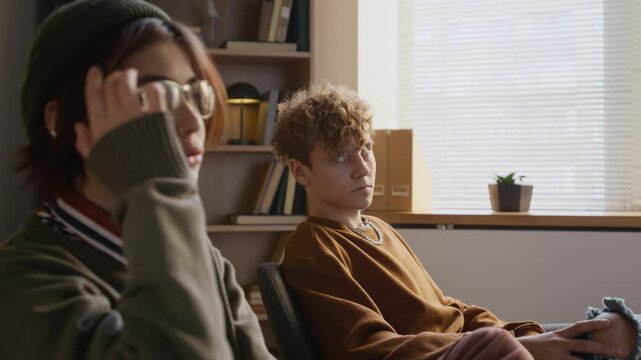 Distressed teenage girl taking in couple therapy holding grudge against resentful boyfriend giving partner side eye glance during conversation in counselling office