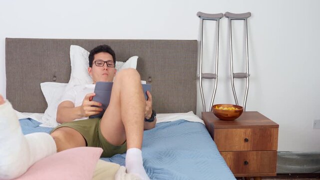 Young man with a leg cast resting in bed at home after an accident