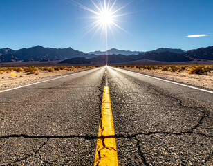 A cracked, endless highway leads toward rugged mountains under a brilliant starburst sun. This scenic desert landscape evokes a sense of freedom and discovery for travel and adventure.