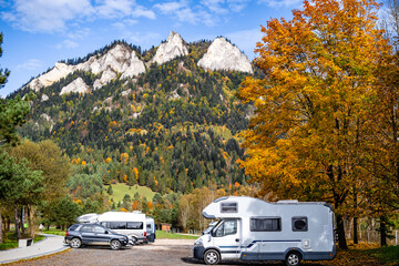 Motorhome camper van parked under autumn tree with mountain landscape