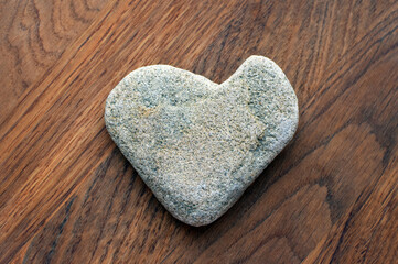 Natural stone in the shape of a heart on a wooden background.