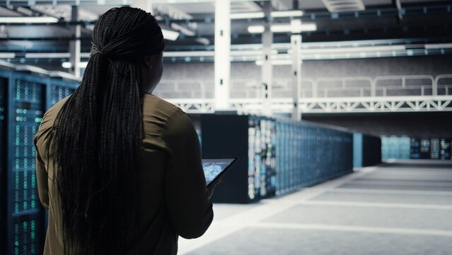 Developer doing data center automation using AI neural networks on tablet. Server room IT professional implements deep learning driven predictive maintenance systems using device, camera A