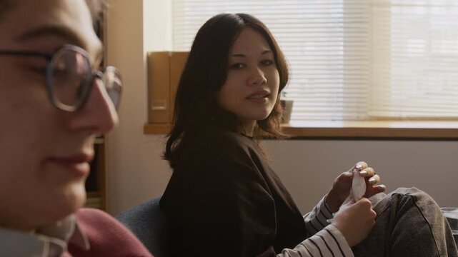 Distressed teenage girl talking to boyfriend about relationship issues during couple therapy session while partner showing resentment towards conversation in counseling office