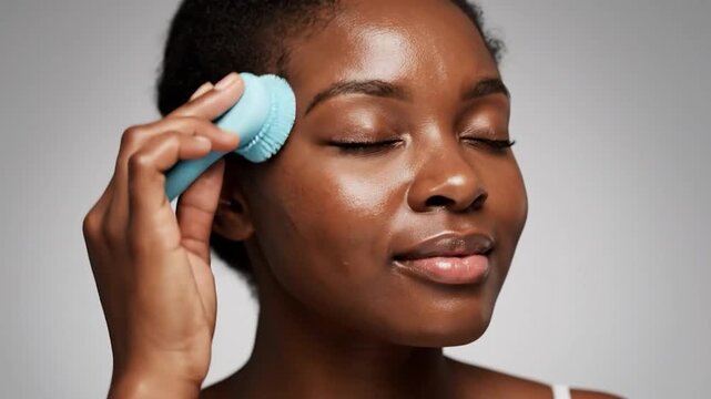 Woman cleansing face with blue sonic brush