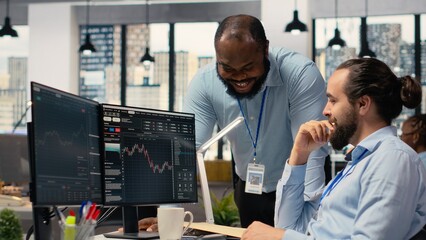 Fototapeta premium Happy coworkers in office doing high five after successful trading strategy on stock market. Joyous teamworking traders at PC desk celebrating, delighted about investment profits