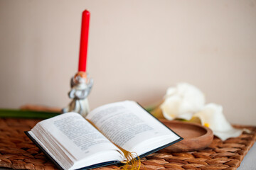 Open Catholic Bible with candle on a woven mat