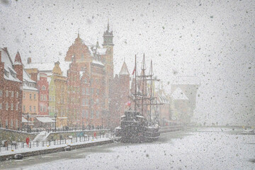 Beautiful ancient sail ship moored on the embankment of frozen Motlawa river in Gdansk