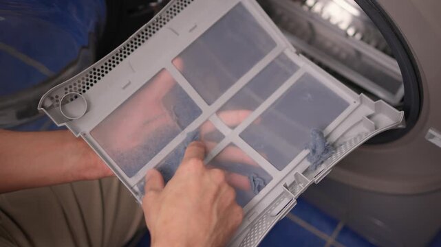 Technician examining dryer lint screen thoroughly, Detailed scene of maintenance technician carefully assessing lint filter inside frontload dryer in laundry room setting