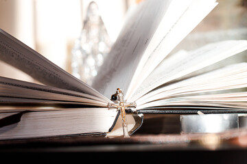 Open Catholic Bible with a cross on a table in light