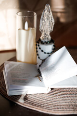 Religious statue and rosary on open Catholic Bible