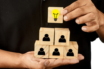 Hand placing an idea symbol above a team structure to represent innovation leadership and creative strategy.
