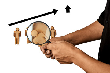 Hand using a magnifying glass to examine a person symbol with upward direction representing performance evaluation.
