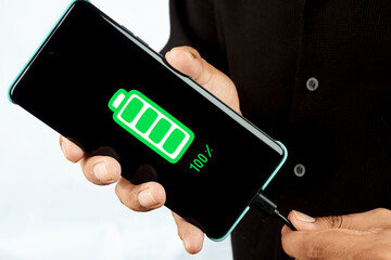 A hand holding a smartphone showing a fully charged battery icon, symbolizing energy readiness, device reliability and continuous digital availability.
