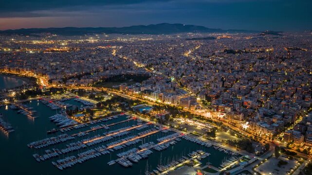 Aerial hyperlapse view of the southern coast of Athens, Greece, with street traffic and city lights during evening time