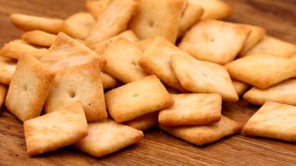 Crispy golden crackers piled on a rustic wooden surface.