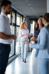 Business professionals networking and discussing ideas in modern office hallway