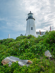 Pemaquid Point Lighthouse in Bristol ME on an early summer day in June with fresh flowers and lush foliage