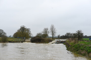 Flooded river after heavy rainfall in countryside. Natural disaster, flooding, extreme weather and climate change concept.
