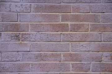 Fototapeta premium Textured brick wall with a blend of muted colors, showcasing the unique patterns and imperfections of the surface, ideal for backgrounds and design projects