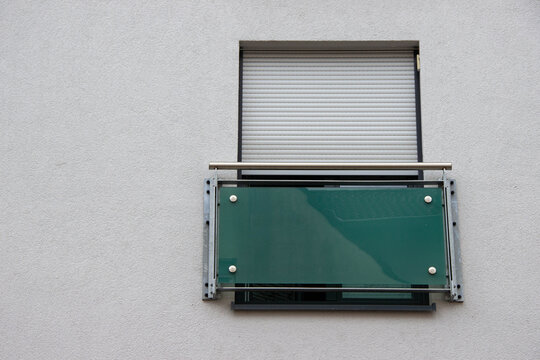Modern balcony design featuring a glass railing and roller shutter window, showcasing contemporary architecture with clean lines and minimalistic aesthetic for urban living
