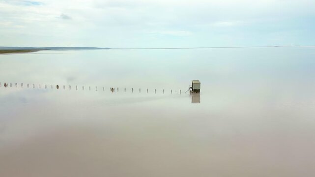 Abandoned wooden structure standing isolated in the pink waters of Tuz salt lake in Turkey
