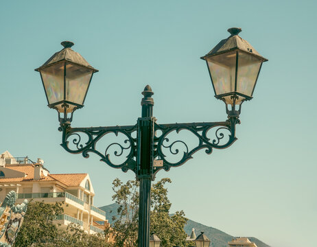 Classic ornate iron street lamp against pale sky.