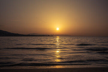 Obraz premium Golden sunset reflection on the calm sea surface.