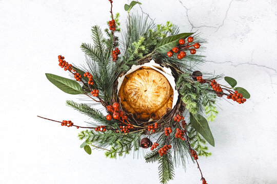 Fresh royal galette with crown and festive wreath on cement table.