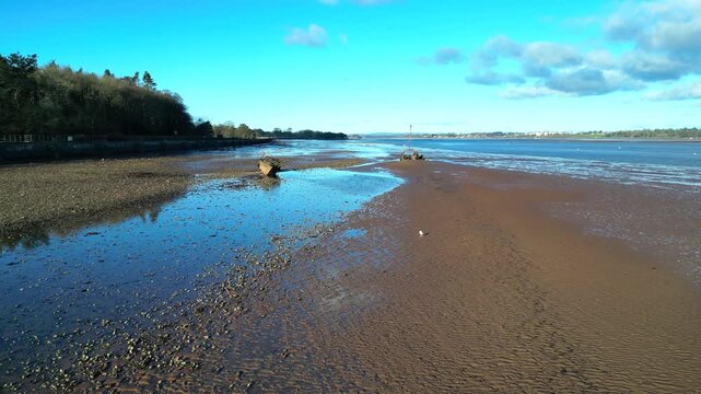 River Exe, Devon, England: DRONE VIEWS: The drone flies low over two boat wrecks exposed on the River Exe mudflats by low tide. The river is 60 miles long and a popular UK tourist destination (Clip 2)