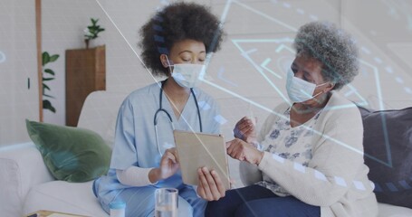Holding tablet, caregiver in light blue scrubs wearing stethoscope and mask, explaining at home