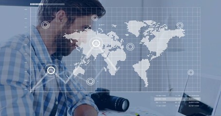 Leaning bearded man wearing checked shirt editing map overlay on laptop in studio, DSLR, copy space