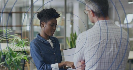 Pointing woman wearing denim shirt showing chart on laptop in modern office, circular overlay