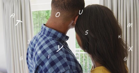 Leaning couple back to camera wearing shirt and top at home viewing glass door white lettering