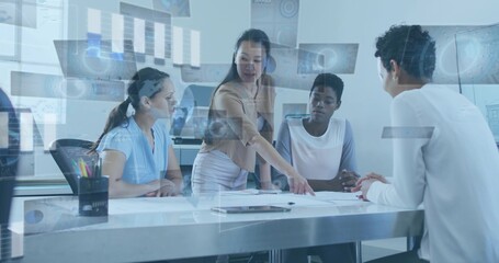 Pointing leader guiding four women in business attire at meeting table, reviewing plans and tablet