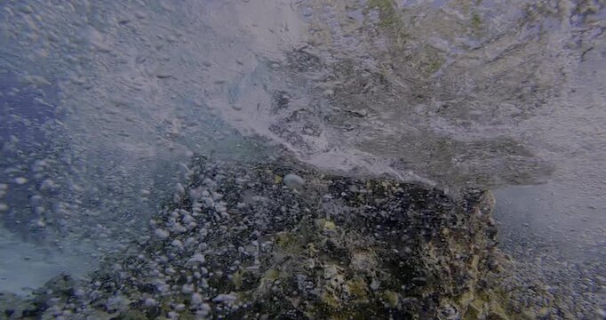 Beautiful Underwater Wave with Air Bubbles in the Blue Ocean Surf Water Flow near a Brown Coral Reef Formation
